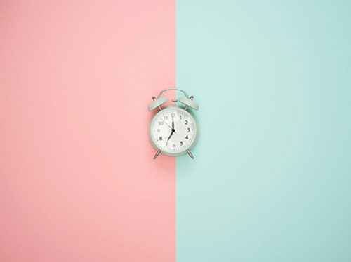 An alarm clock on a colored background, with one side pink and the other side blue icon
