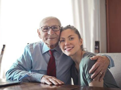 A smiling elderly man with his hand around a smiling young woman's shoulder icon