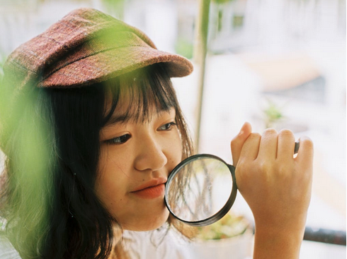 Woman wearing a hat and a magnifying glass in the style of a detective icon