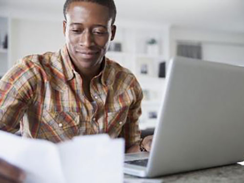 A man with a laptop looking at a piece of paper and smiling icon