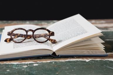 A pair of glasses on top of an open book icon