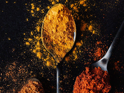 Spoonfuls of spices on a black background icon
