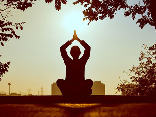 A person doing a yoga pose in front of the sun icon
